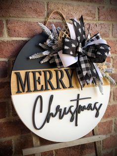 a merry christmas sign hanging on the side of a brick wall with black and white bows