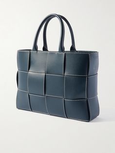 Bottega Veneta specialises in quiet luxury and understated elegance. In a scaled-down version of the label's signature intrecciato weave, this 'Mini Arco' tote bag has been crafted in Italy from navy leather with contrast stitching and left unlined to show off the expert workmanship. The brand recommends filling it with tissue paper to maintain its shape and absorb humidity when stored away. Porter Bag, Latest Bags, Leather Messenger Bag, Navy Leather, Leather Messenger, Leather Pouch, Green Bag, Black Tote Bag, Leather Care