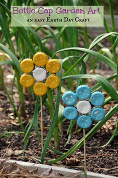 two plastic flowers sitting in the dirt next to some green grass with text overlay that says bottle cap garden art an easy earth day craft