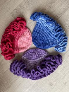 three crocheted hats laying on top of a wooden floor next to each other