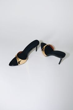 Our best selling Gia Mules reimagined in a 80 mm heel. Gia is a minimal mule that will garner all the attention. Mirrored Gold Upper Strap & Glossy Black Vegan Patent Leather insole. Size and Fit Information: U.S. Sizing Available in whole and half sizes Runs true to size (Note: Not using leather and other materials from animals significantly reduces environmental impact, however, we acknowledge that synthetic alternatives are not without environmental concerns. As we grow, we are dedicated to f Modern Open Heel Heels For Evening, Modern 4-inch Kitten Heels For Party, Modern Mules With 4-inch Heel For Night Out, Chic Mules With 4-inch Heel And Single Toe Strap, Modern Heels With Single Toe Strap For Night Out, Modern Heels With Single Toe Strap For Evening, Modern Evening Heels With Single Toe Strap, Sleek Evening Mules With Sculpted Heel, Sleek Office Mules With Contrasting Heel Counter