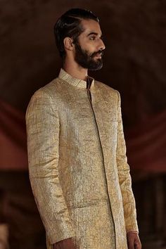 God textured lampi sherwani with chanderi organza kurta and striped lycra pants.
Component: 3
Embroidered
Neckine: Sherwani: Mandarin Collar
Sleeve Length: Sherwani: Full
Fabric: Sherwani: Lampi; Kurta: Organza, Chanderi, Pant: Lycra
Color: Gold

Side slits
Striped pattern
Closure: Sherwani: Concealed front placket - Aza Fashions Gold Sherwani, Sherwani Jacket, Organza Kurta, Blouse Yoke, Traditional Fashion, Indian Ethnic Wear, Gold Stripes, Gold Texture, Designer Wear