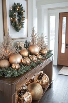 an entryway decorated for christmas with gold ornaments and greenery on the side table