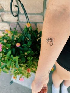 a woman's arm with a strawberry tattoo on the left side of her body