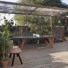 a ping pong table in the middle of a wooden deck with potted plants