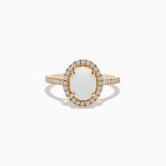 a gold ring with an oval shaped white stone surrounded by small round diamond halos