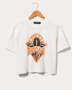 Step up your Bengals game-day look with the Women's Bengals Mock Neck Crop Tee! This NFL-licensed apparel combines Cincinnati Bengals pride with a sleek mock neck design. With its flattering crop cut and sporty logo, you'll stand out in style while cheering for your team. Perfect for fashion-forward football fans! Shop the rest of our Women's NFL Collection HERE. Cincinnati Bengals Sweatshirt, Sporty University Logo T-shirt With Crew Neck, Streetwear Top With Team Logo, Team Logo Tops For Streetwear, Varsity Crew Neck Top With Team Logo, Cropped Crew Neck T-shirt With Graphic Print For College, Graphic Tee With Team Logo And Crew Neck, Crew Neck Tops With Team Logo For Sports Events, Team-colored Tops With Team Name For Streetwear