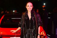 a woman standing in front of a red car