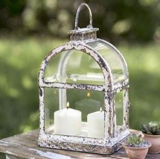 two white candles are in a glass lantern