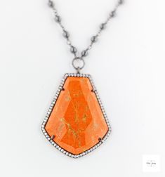 Stand out in this beautiful eye-catching burnt orange resin, hematite and cubic zirconia necklace. Bold and bright it is ready for your next event and bound to get you noticed! The beautiful uniquely shaped burnt orange resin bezel has shimmering ribbons of saffron yellow throughout and it is framed by sparkling cubic zirconia stones.Stunning, bright and shimmering faceted cherry burnt orange resin framed by black gold-plated sterling silver bezel that is studded with sparkling cubic zirconia. Black gold-plated short and long oval link chain. Beautiful shimmering silvery black hematite beads wrapped in black gold-plated chain. Gunmetal-plated brass lobster clasp for a secure and comfortable fit. 18.5 inches long. Only one available! Make this gorgeous limited edition necklace yours today!