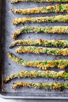 cooked asparagus with parmesan cheese and seasoning on a baking sheet