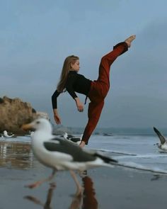 a woman standing on one leg in front of seagulls and the other bird