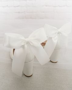 a pair of white shoes with bows on them