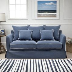 a blue couch sitting in front of a window next to a striped rug and lamp