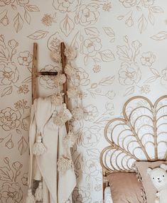 a bed with a wooden headboard next to a wall papered with flowers and leaves