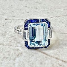 Breathtaking handcrafted platinum Art Deco style aquamarine, sapphire and diamond halo cocktail/engagement ring! It is set with a fine emerald cut aquamarine weighing 3.23 carats (10.02 x 8.07 mm). It is haloed by a row of natural French cut blue sapphires weighing approximately 1/2 carat. It is accented by 2 baguette diamonds and 6 old European cut diamonds weighing approximately 0.35 carat. Fine milgrain add to the delicacy of the ring. Beautiful openwork filigree decorate the under gallery. L: 14.05 mm W: 13.34 mm Band width: 1.78 mm Ring size 6.5 US / M 1/2 UK / 52 3 /4 FR. This ring is part of the Authenticity Guarantee program of eBay. For this reason we are unable to resize if bought on eBay. Please visit our website WeiLJewelry to purchase and resize this ring. Birthstone: March/Ap Art Deco Sapphire Ring, Ruby Diamond Rings, Diamond Halo Ring, Aquamarine Engagement Ring, Aquamarine Jewelry, Deco Engagement Ring, Aquamarine Rings, Halo Diamond Ring, Art Deco Diamond