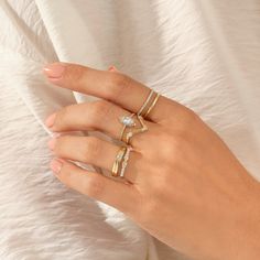 a woman's hand with three different rings on top of her finger and the other ring