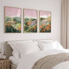 two paintings on the wall above a bed in a bedroom with white linens and pillows