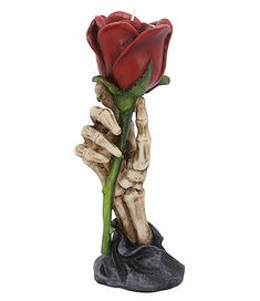 a red rose sitting on top of a rock next to a black hand holding it