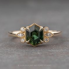 a close up of a ring with a green stone and diamonds on the bottom side