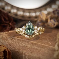 a close up of a ring with a green stone in the middle and white stones around it