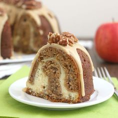 a bundt cake on a plate with a fork and an apple in the background