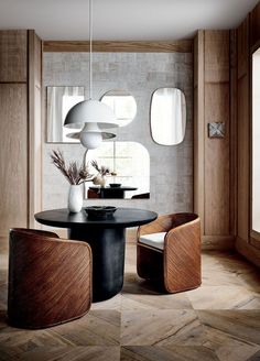 a dining room table with chairs and a vase on top of it in front of a window