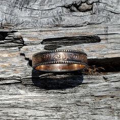 a wedding ring sitting on top of a piece of wood with an intricate design in the middle