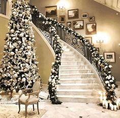 a staircase decorated with white flowers and greenery next to a christmas tree on the floor