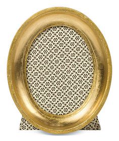 a gold plate sitting on top of a white tablecloth covered placemat with an intricate design