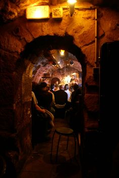 a group of people are sitting in a cave with lights on the ceiling and one person is standing up