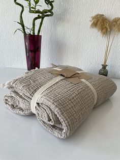 two towels folded on top of each other next to a vase with flowers in it