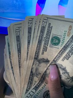 a person holding money in their hand on top of a counter with blue lights behind them