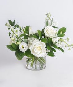 a vase filled with white flowers and greenery