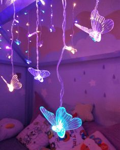 some lights that are hanging from the ceiling in a room with a bed and pillows