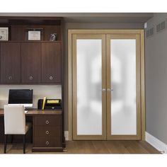 a home office with glass doors and wooden cabinets, along with a computer on the desk