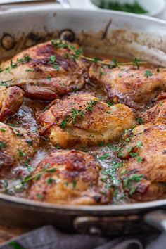 a pan filled with meat and sauce on top of a wooden table