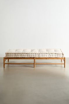 a wooden bench sitting on top of a cement floor next to a white wall in an empty room