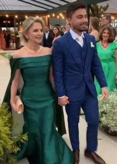 a man in a blue suit and woman in a green dress walking down a walkway