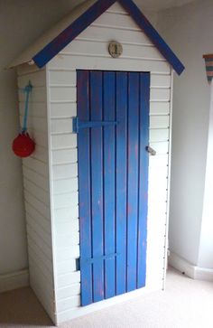 a white and blue storage shed sitting on top of a carpeted floor