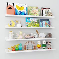 three white shelves filled with books and toys