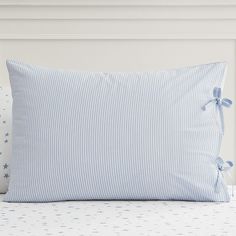 a blue and white striped pillow sitting on top of a bed next to two pillows