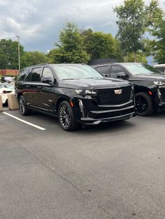 two black suvs parked in a parking lot