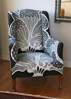 a black and white chair sitting on top of a wooden floor next to a mirror