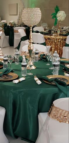 the table is set with green cloths and gold place settings