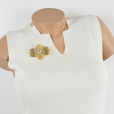 This lovely Gianfranco Ferre couture pin brooch features a dimensional gilt metal geometric shape, all paved with crystal clear rhinestones and topped with two massive champagne resin cabochons. A security closing clasp at the back with the Ferre, Made in Italy hallmark underside. Measurements: 2.50 in wide (6.3 cm) x 2.07 in high (5.2 cm).  Please see the measurements noted above in the description for the best approximate dimensions. Designer Gold Brooches For Party, Formal Gold Jeweled Brooches, Gold Jeweled Brooches For Formal Occasions, Chic Gold Brooch For Evening, Gold Wedding Brooches Chic Style, Gold Wedding Brooches In Chic Style, Gold Chic Wedding Brooches, Chic Gold Wedding Brooch, Chic Gold Wedding Brooches