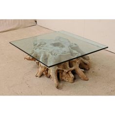 a table made out of driftwood with glass top on the floor in front of a wall