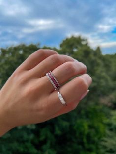 a woman's hand with a ring on it and trees in the back ground