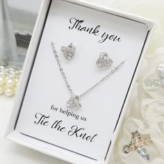 a gift box with two pieces of jewelry in it and the words thank you for helping us tie the knot