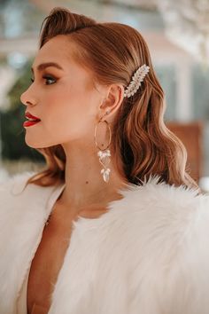 a woman wearing a white fur coat and earrings